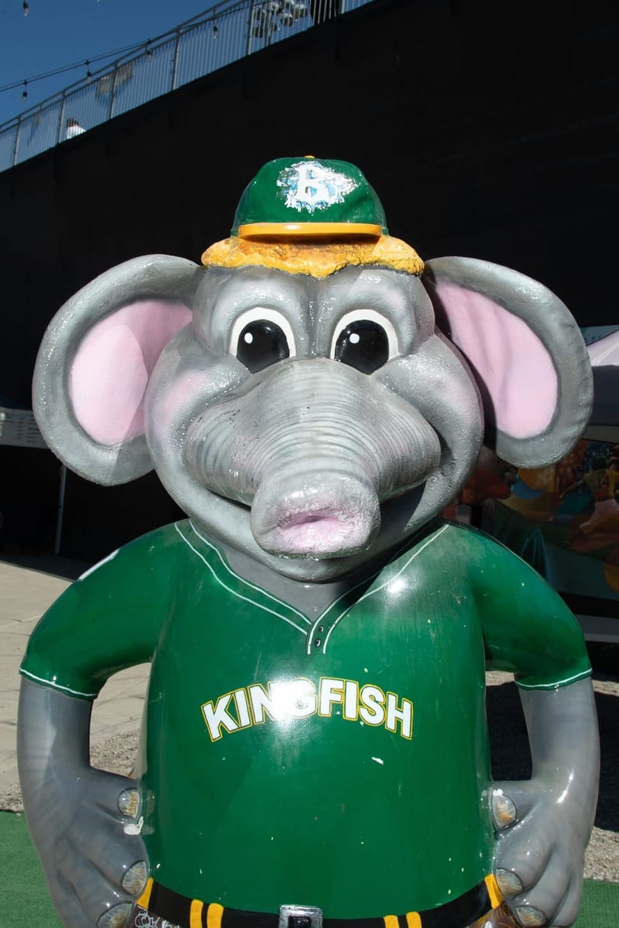 A statue of an anthropomorphic elephant wearing a green baseball jersey that says "Kingfish" on it.