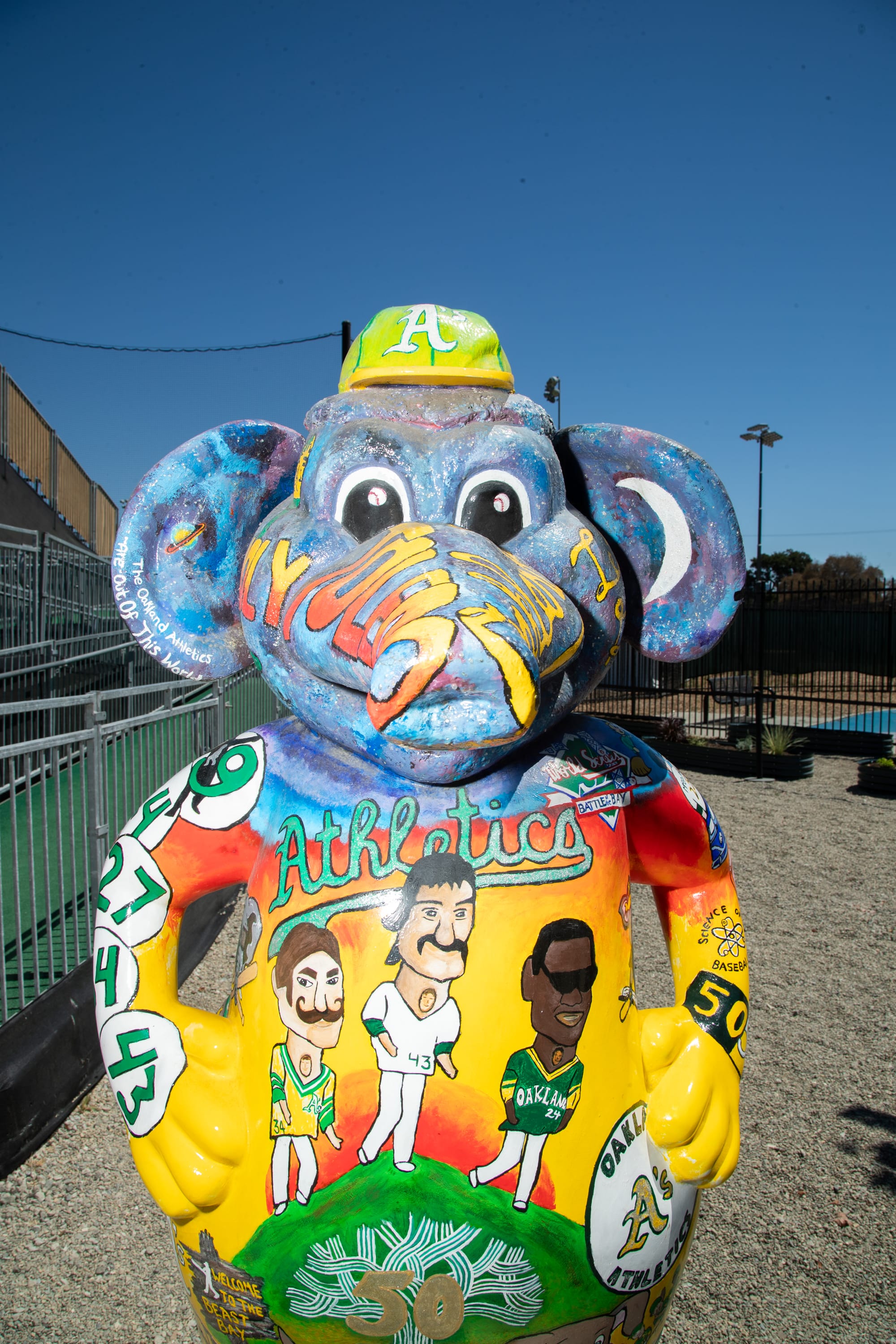 Statue of a blue anthropomorphic elephant with three human baseball players painted on its torso.