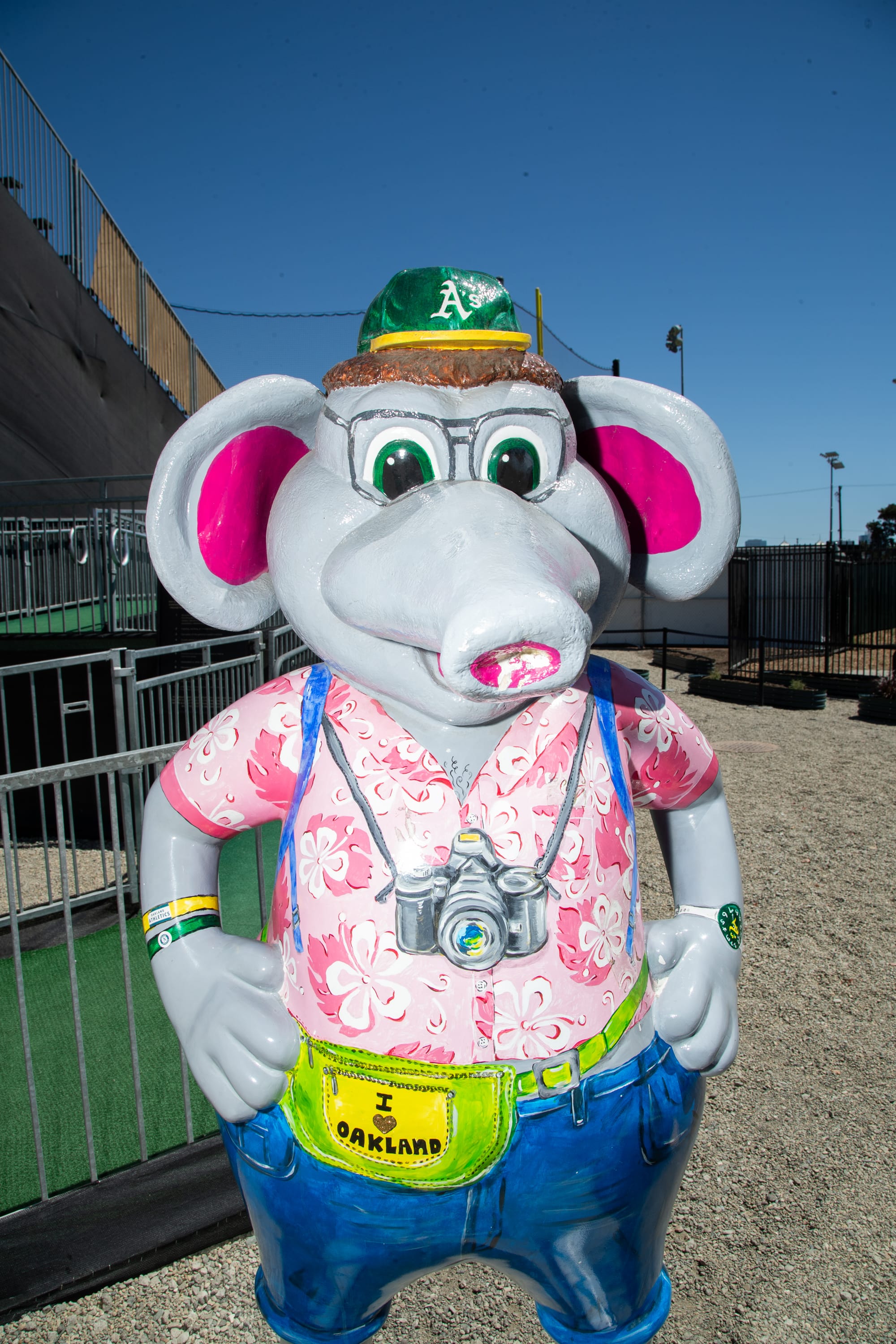 An anthropomorphic elephant statue painted with glasses, a Hawaiian shirt, a camera, and fanny pack.