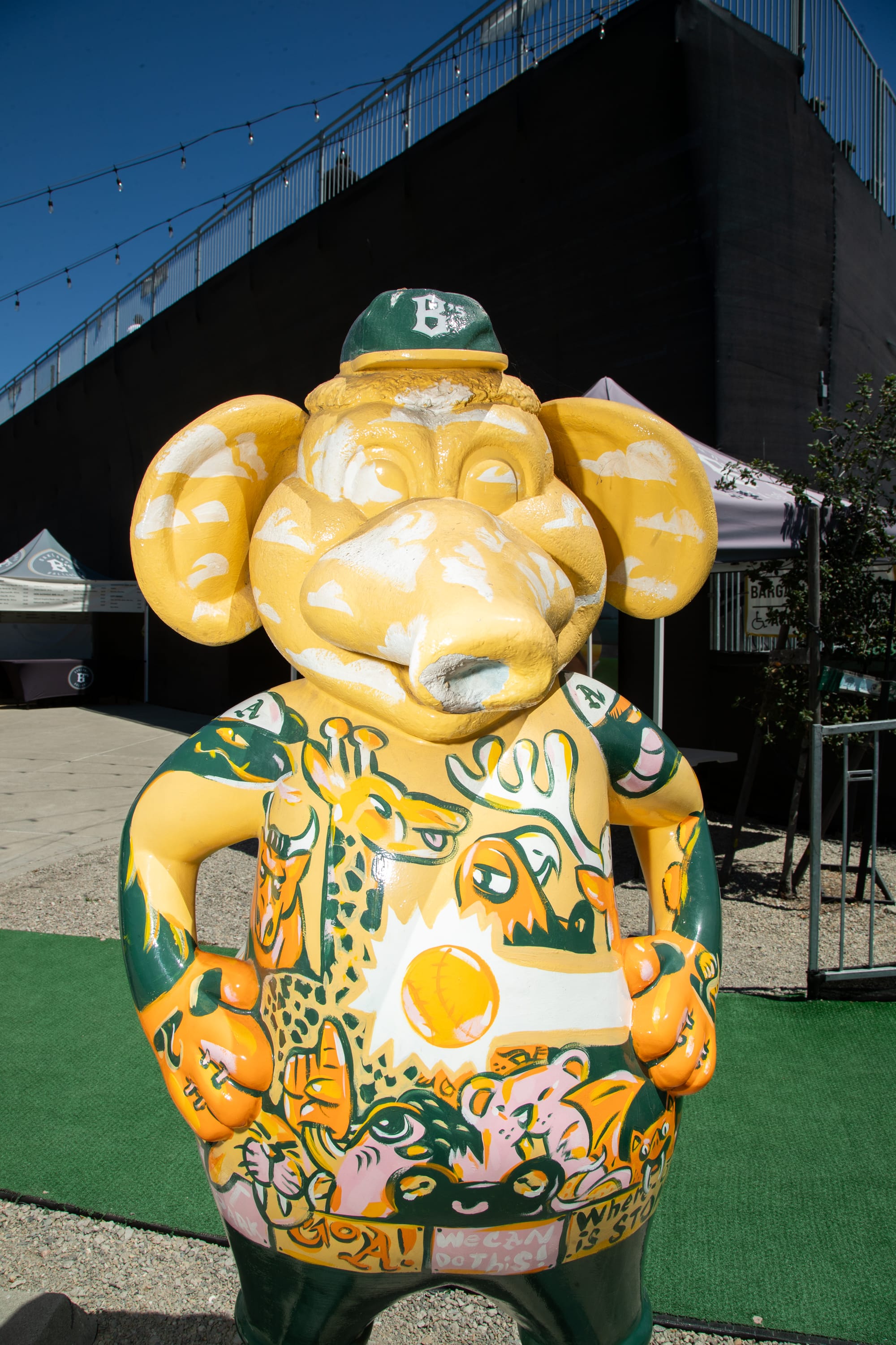 A yellow statue of an anthropomorphic elephant painted with cartoon animals on its torso.