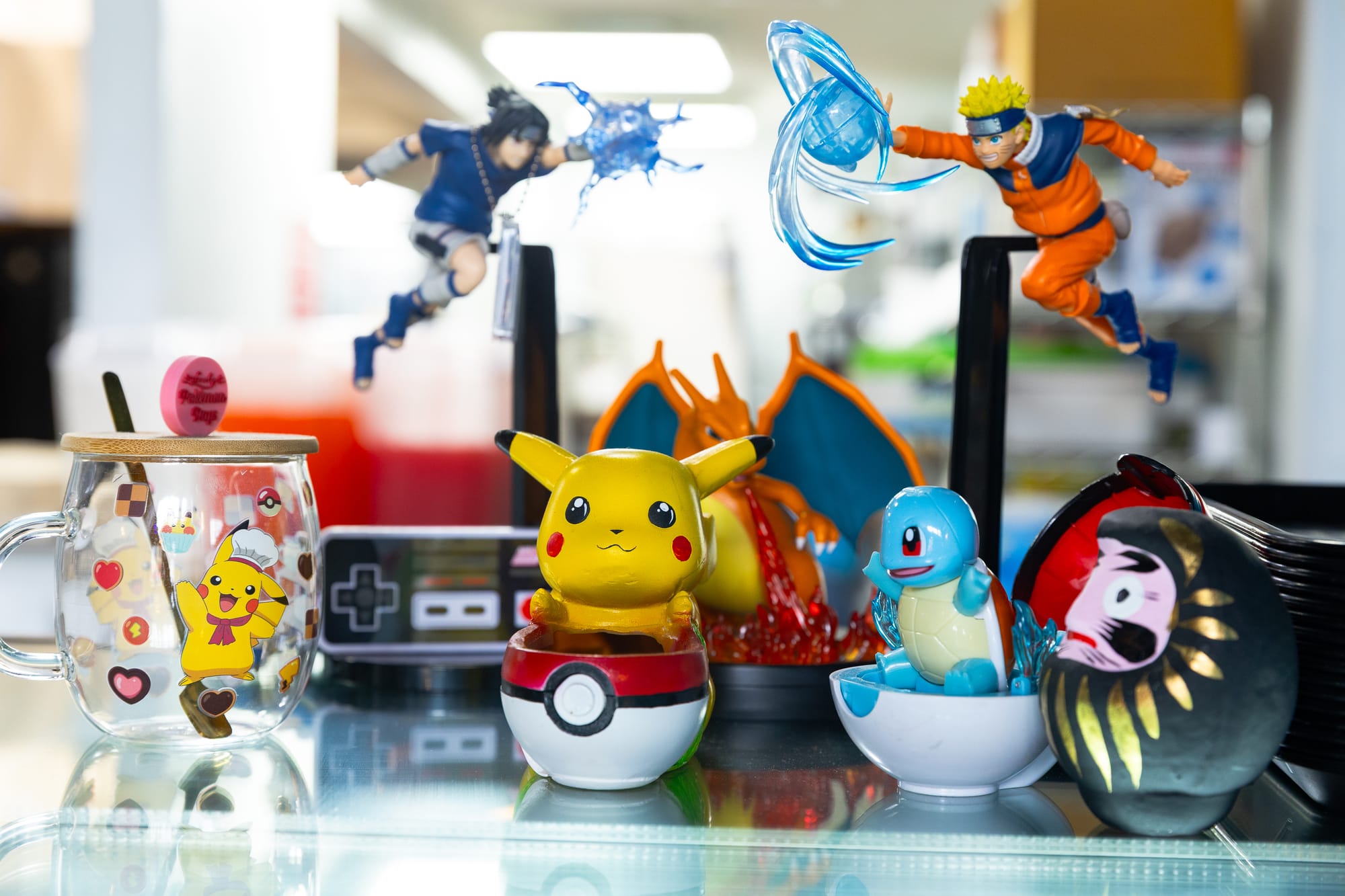 Collection of small Pokemon and Naruto toys on a glass counter.