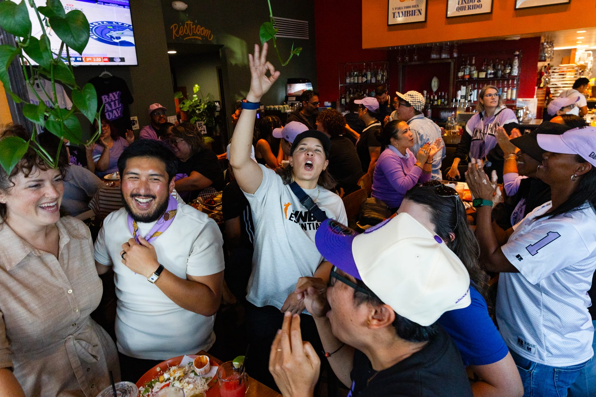 young people cheer and smile in a crowded sports bar