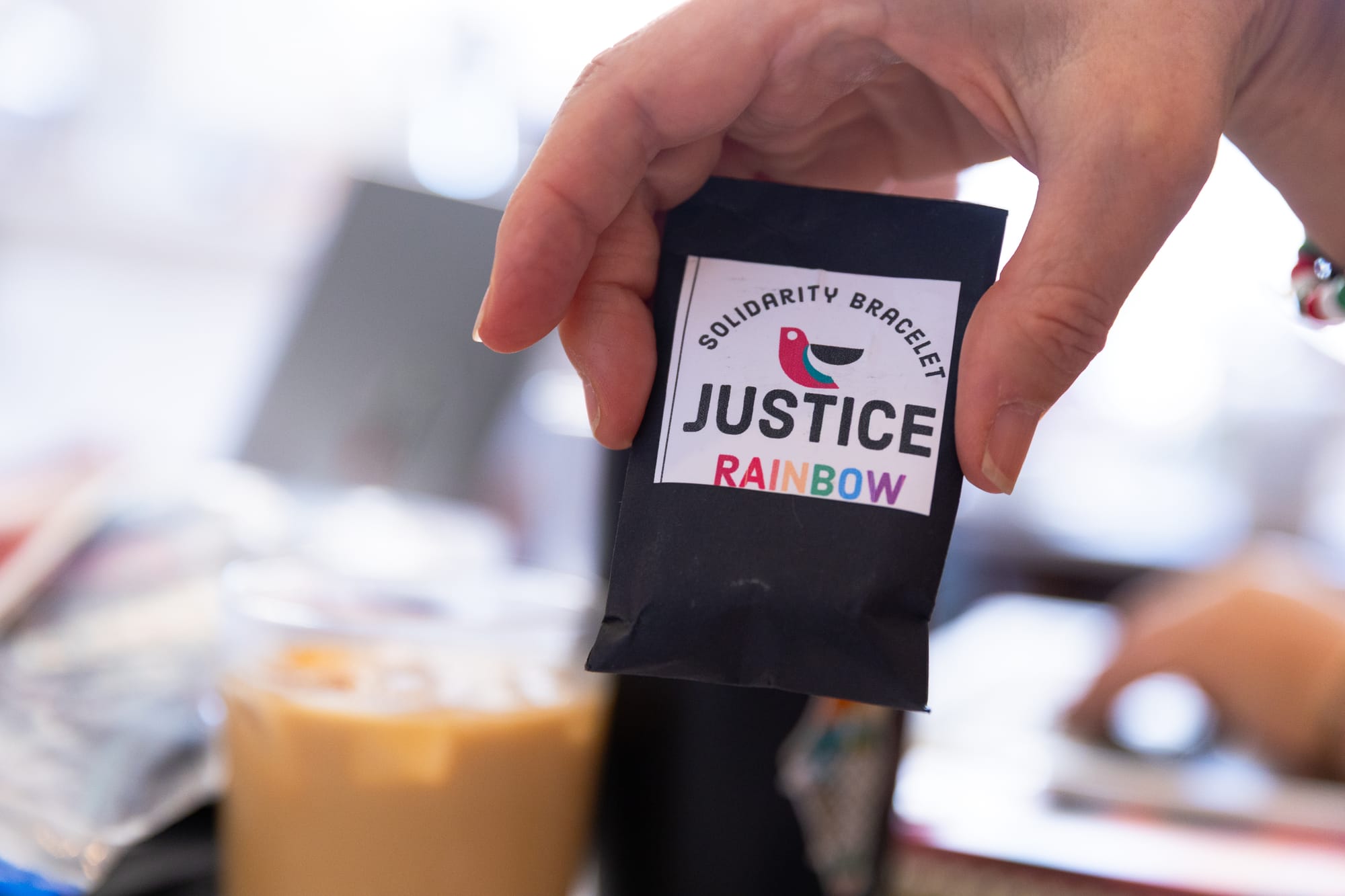 a close-up of hands showing a package that reads 'solidarity bracelet - justice rainbow'