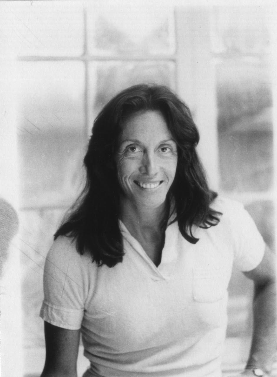 A woman in a white polo shirt with long dark hair poses for the camera.
