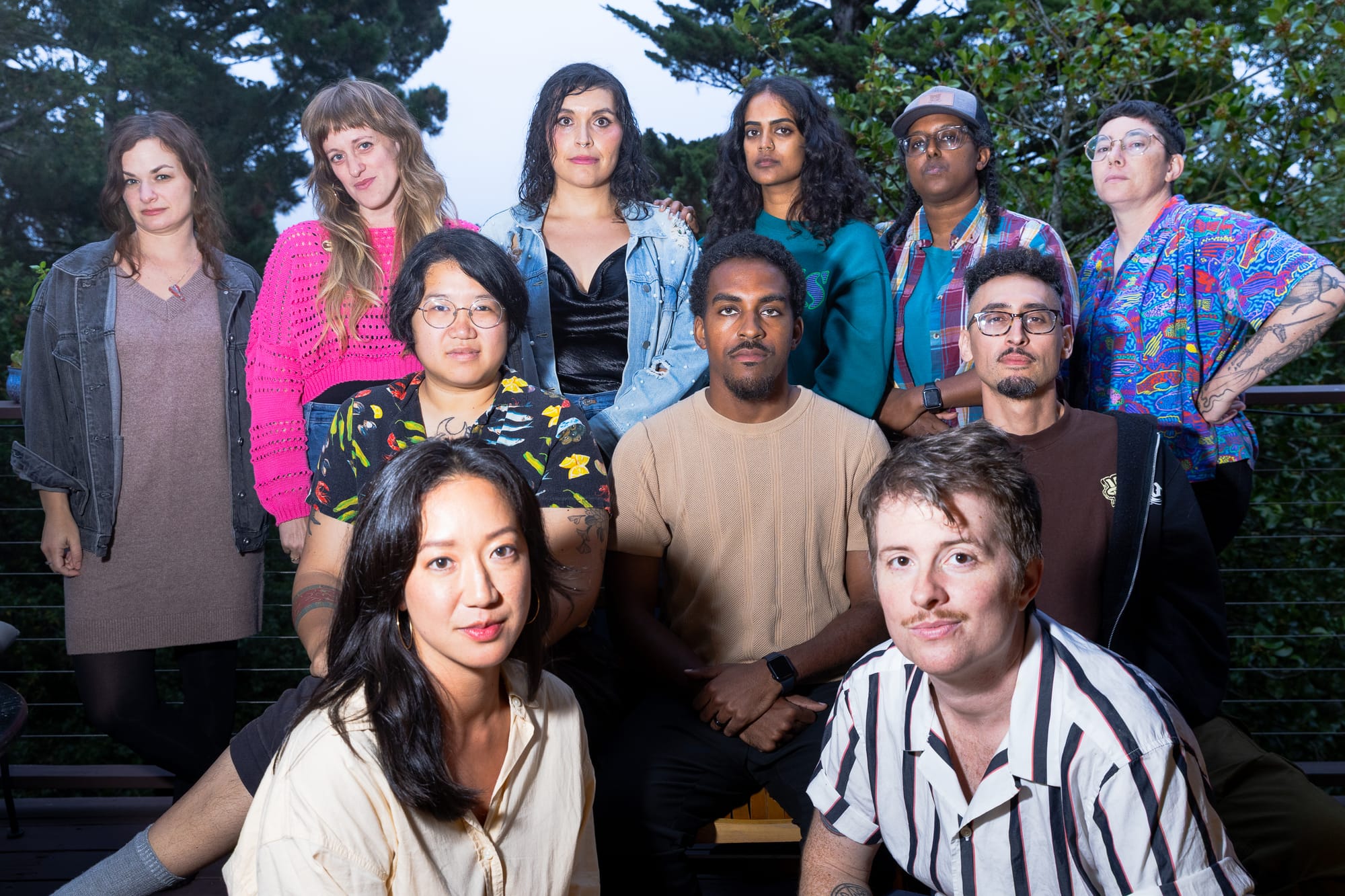 11 people arranged in three rows looking at the camera