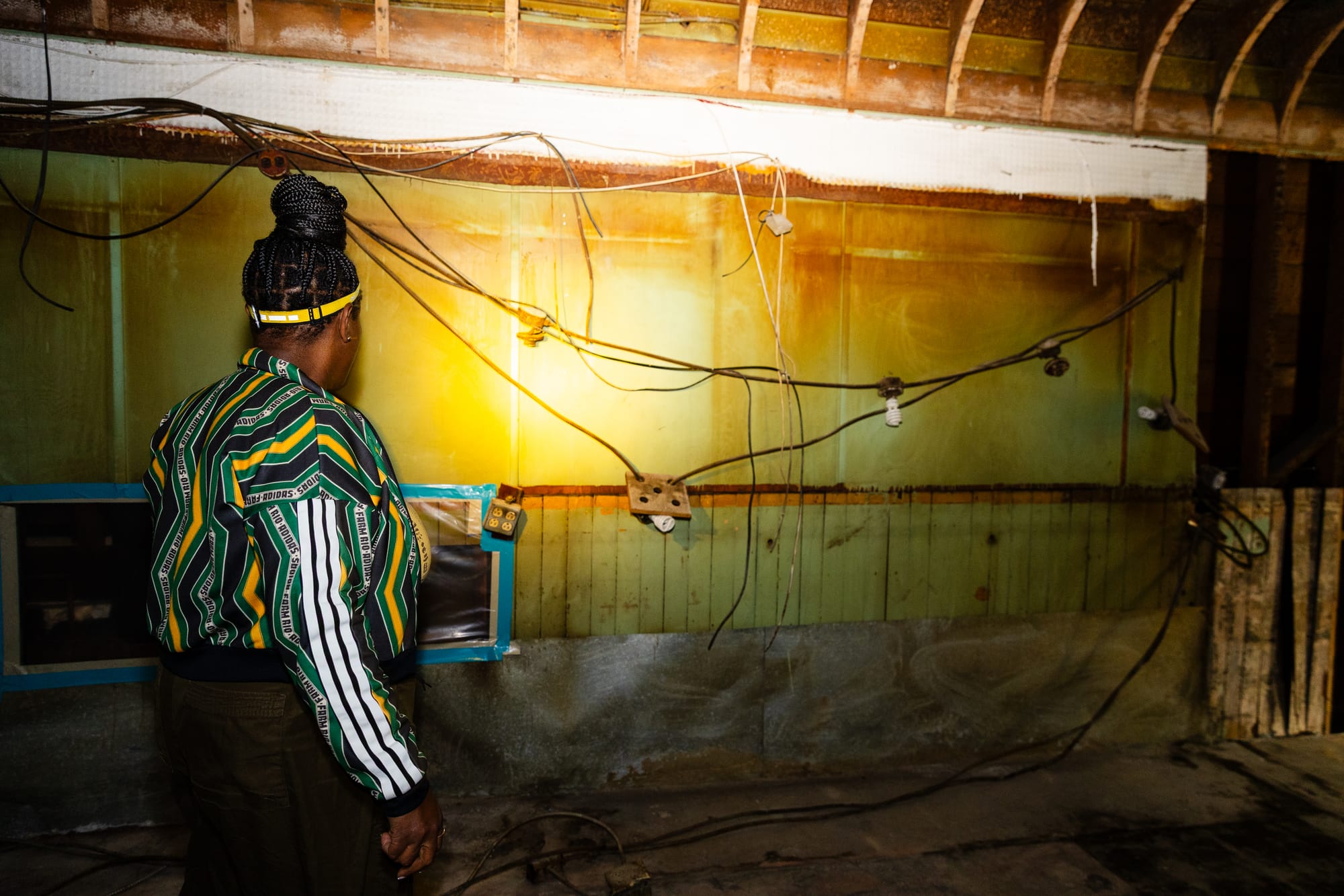 Noni Session looks at a yellowed wall inside of the club.