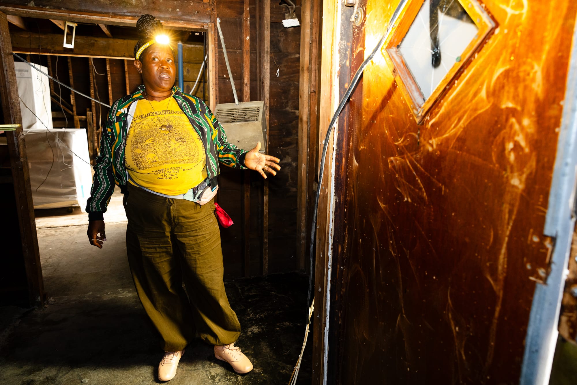 Noni Session stand in dimly lit a construction site wearing a headlamp.