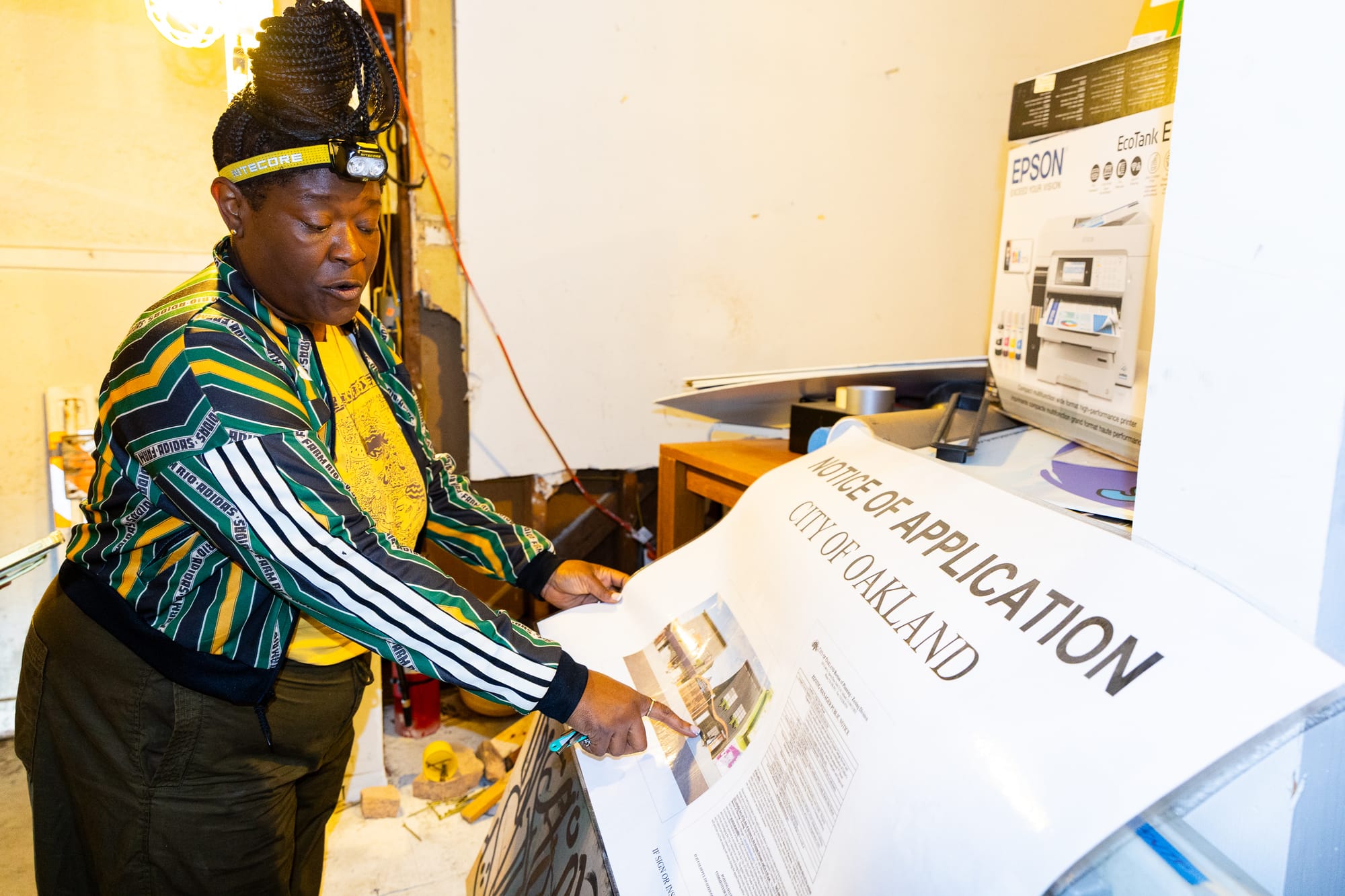 Noni Session points at a large sign displaying her construction application