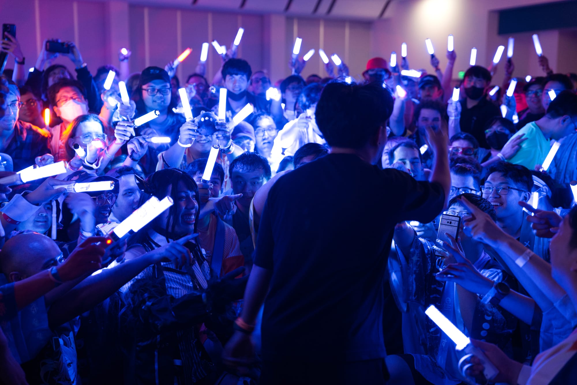 A crowd of fans wave glowsticks.