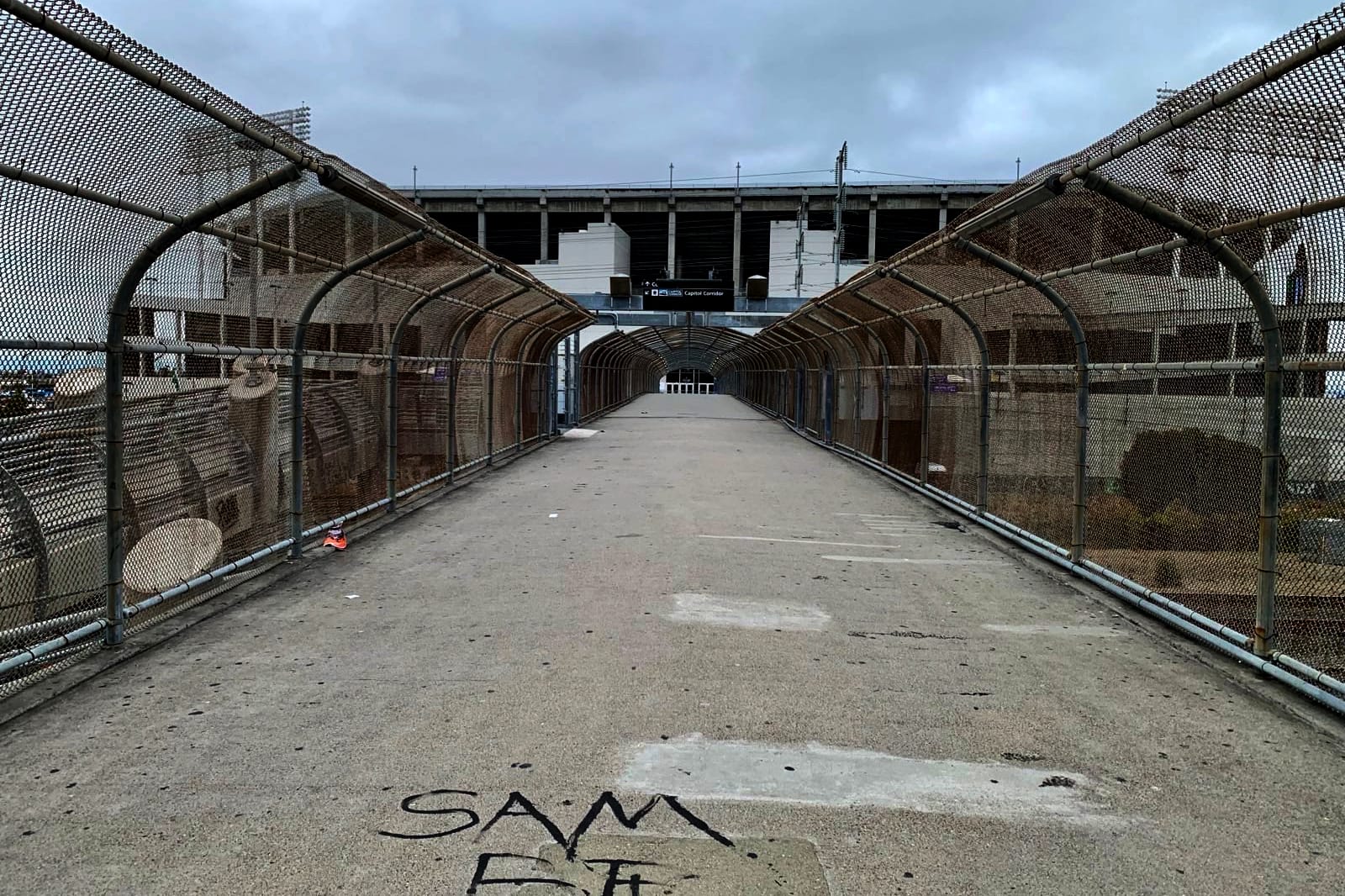 A deserted concrete walkway leading toward the Coliseum on a dreary morning.