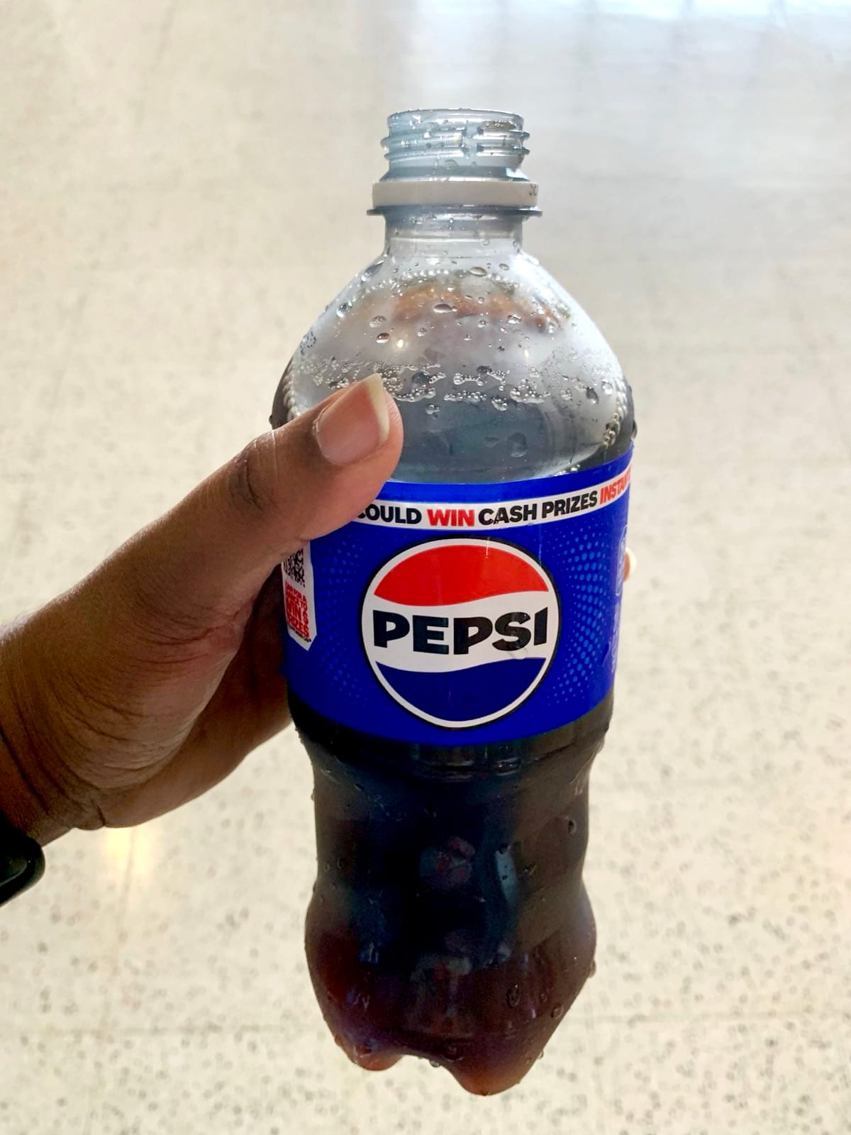A person holds a bottle of Pepsi