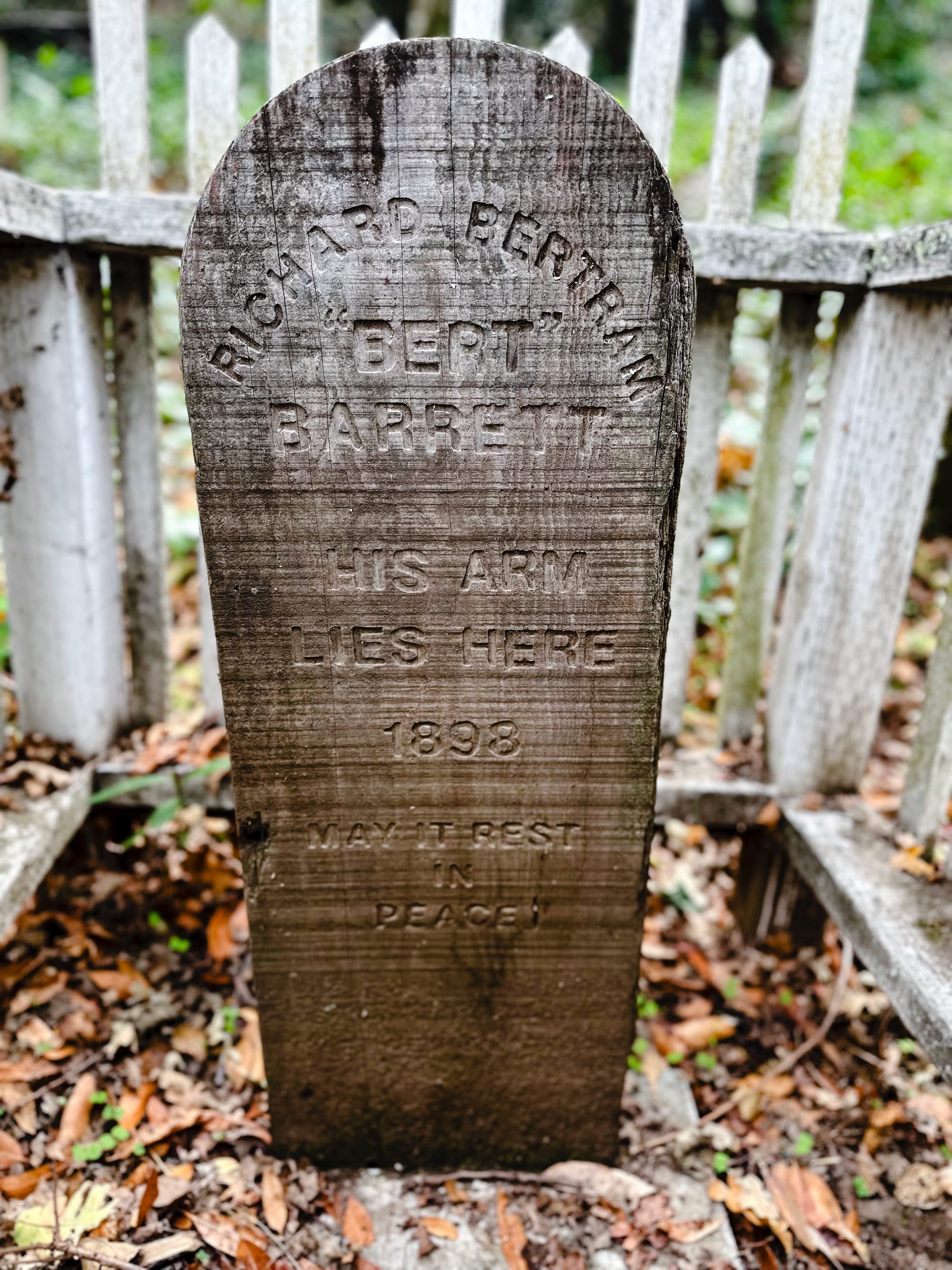 A headstone reads, "His arm lies here. May it rest in peace"