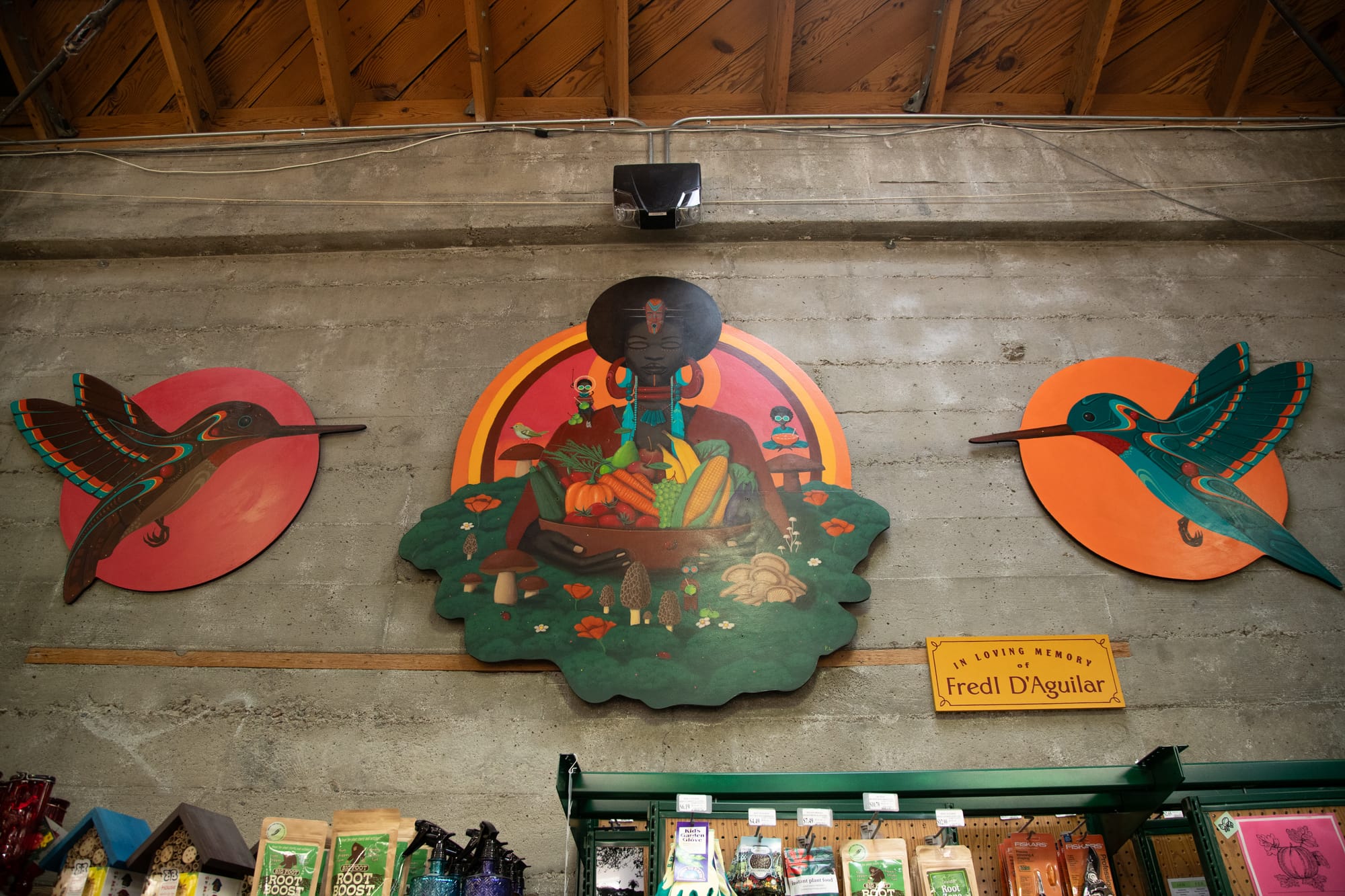 a mural of produce displayed inside a grocery store with a sign that reads 'in loving memory of Fredl d'aguilar'