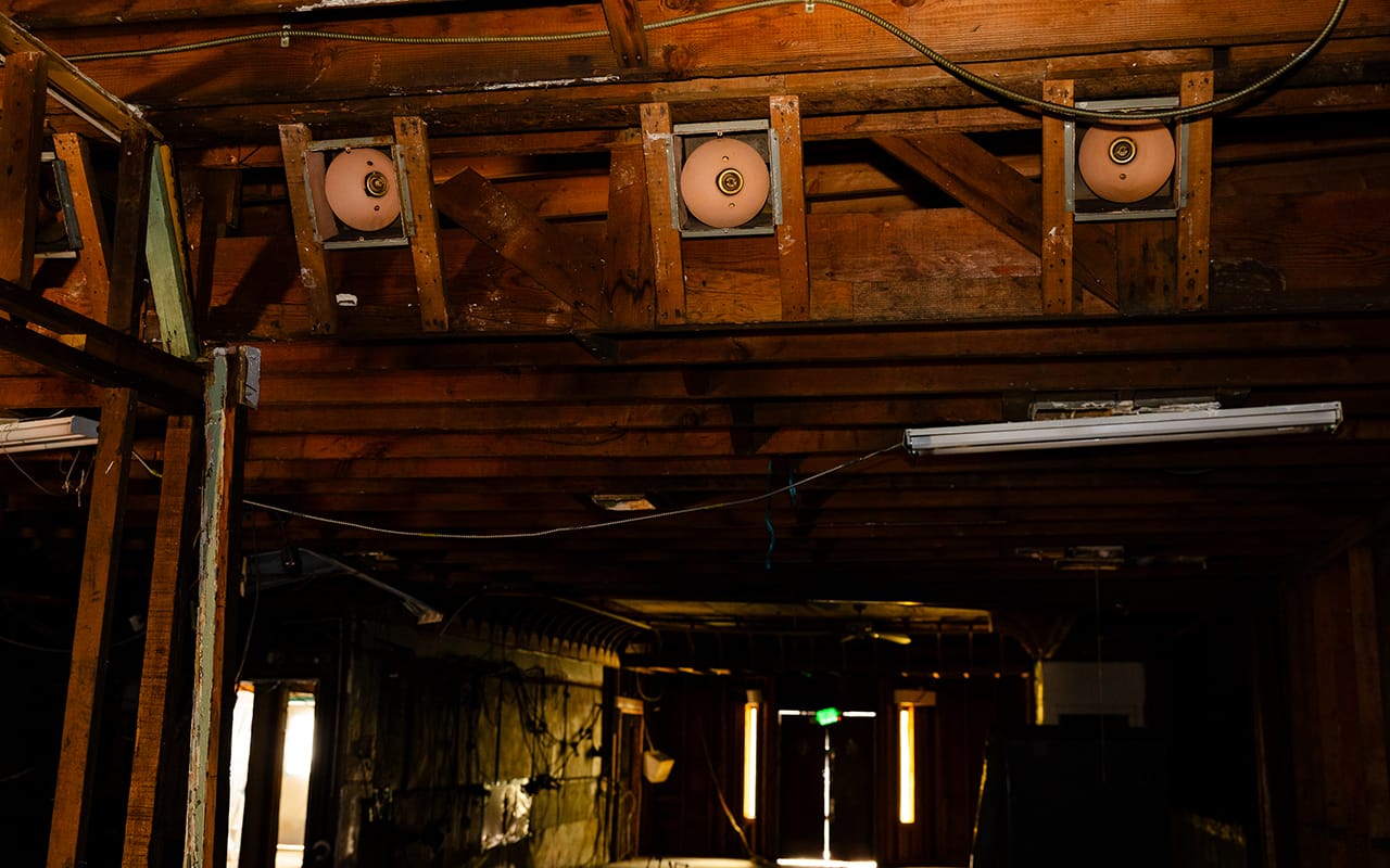 Old-style stage lights mounted in a wooden ceiling