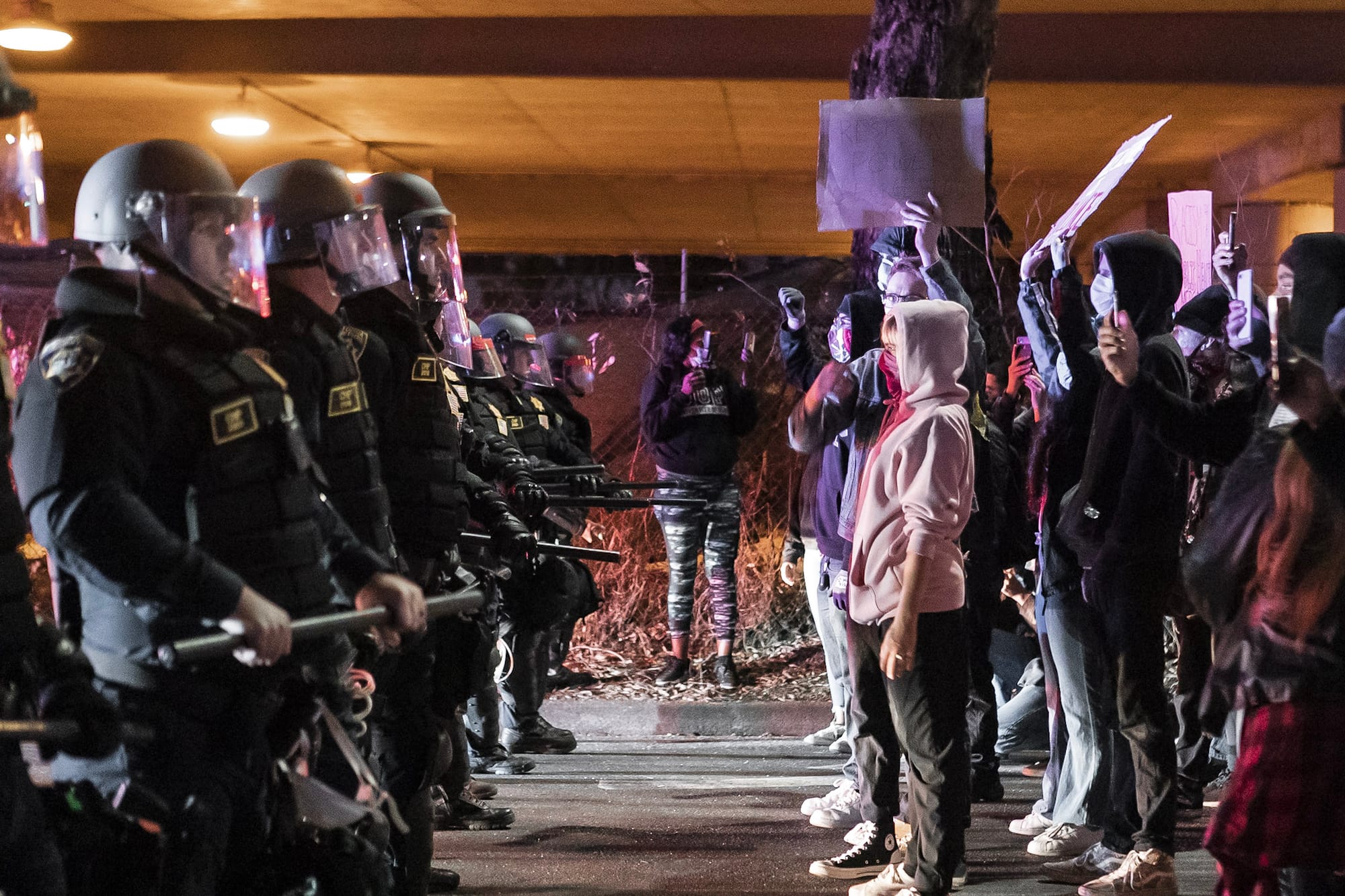 Protesters stand next to line of police officers.