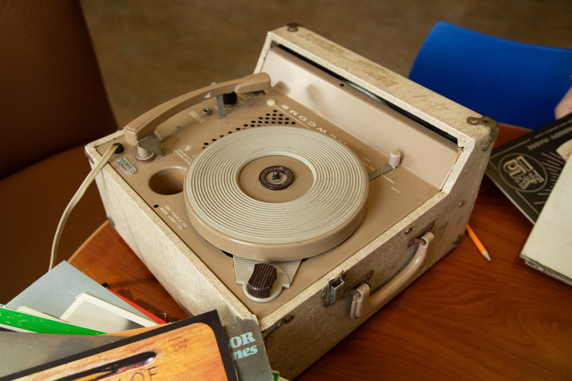 a close-up of a very old tan record player on a table with vinyl records