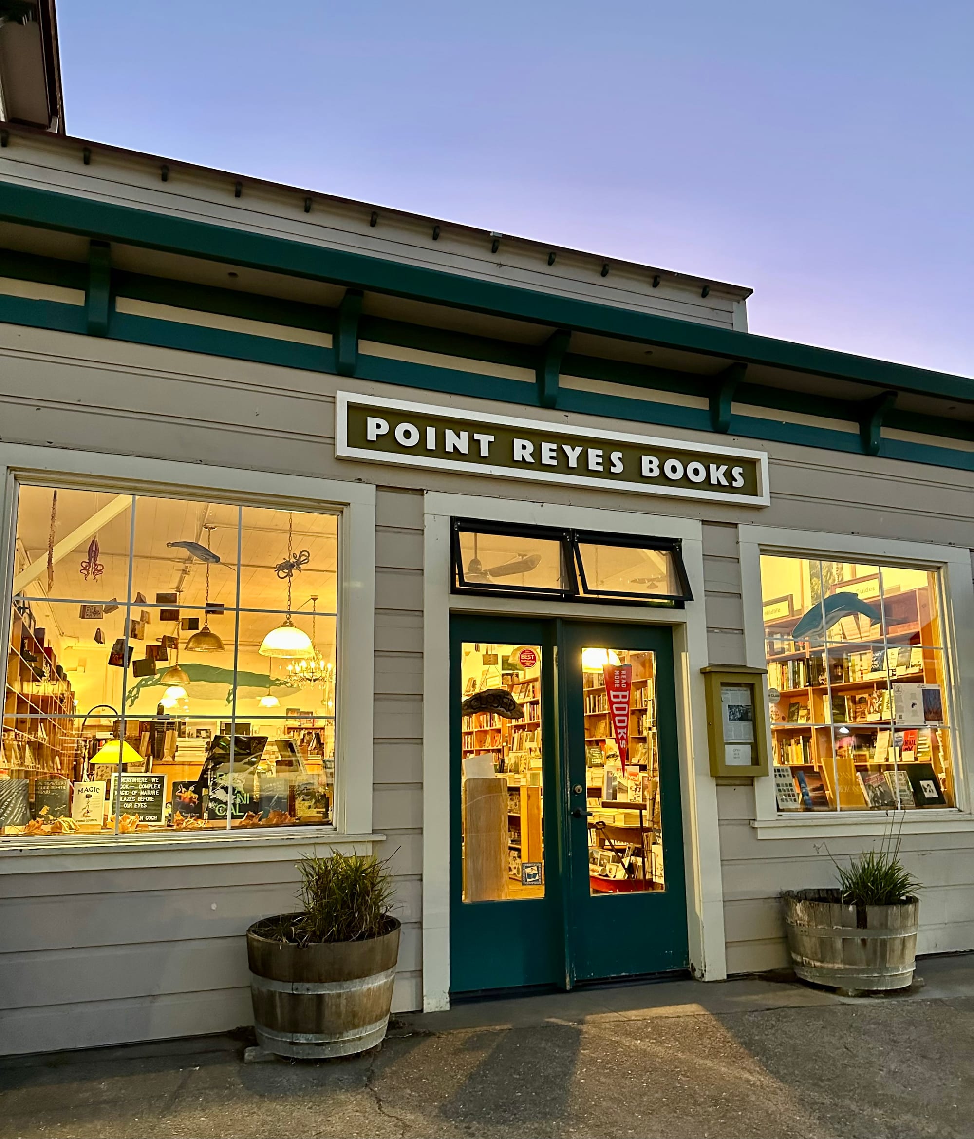 a storefront with a sign that says 'point reyes books,' the shop is warmly lit and you can see many books inside