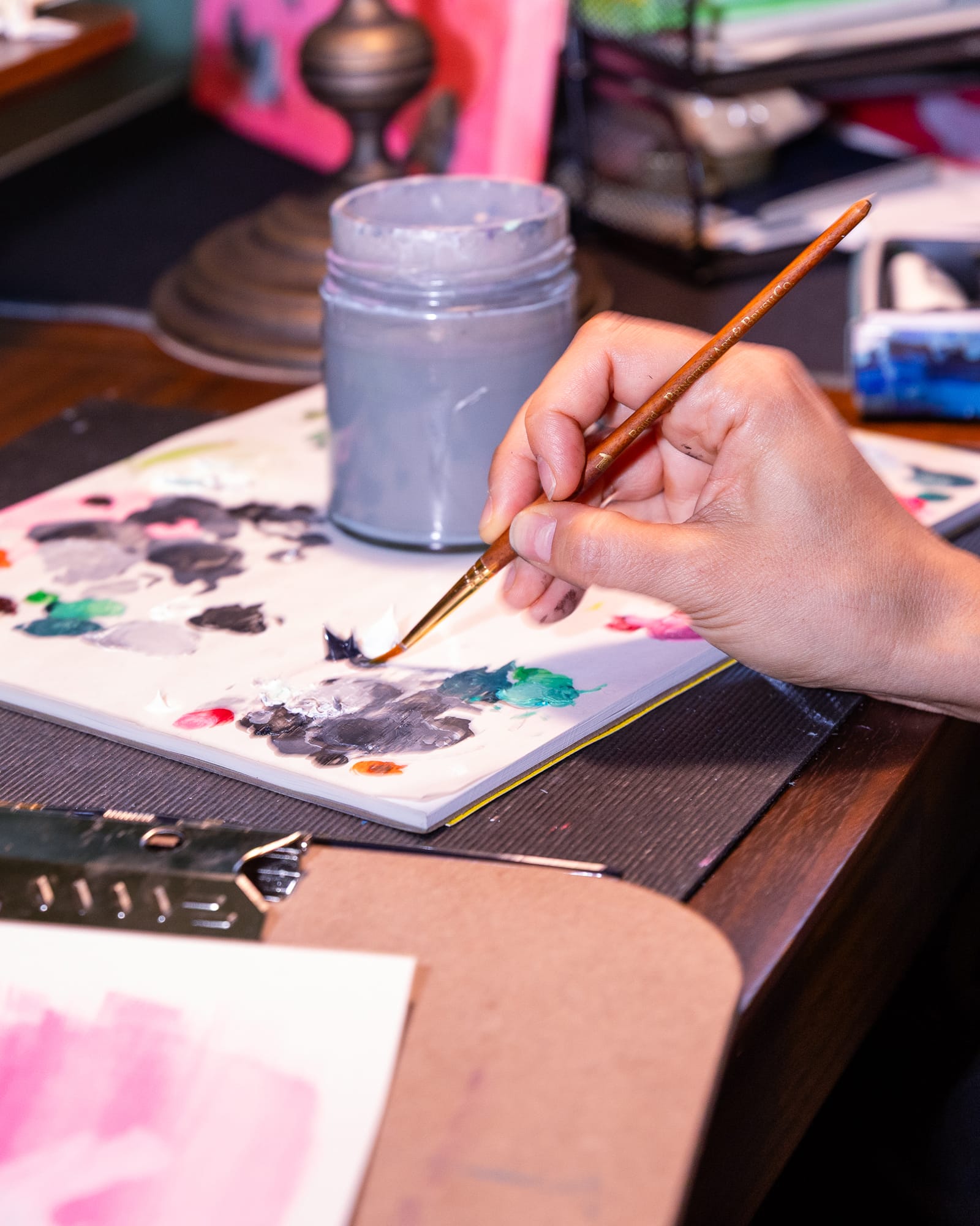 A hand mixing colors with a paintbrush.