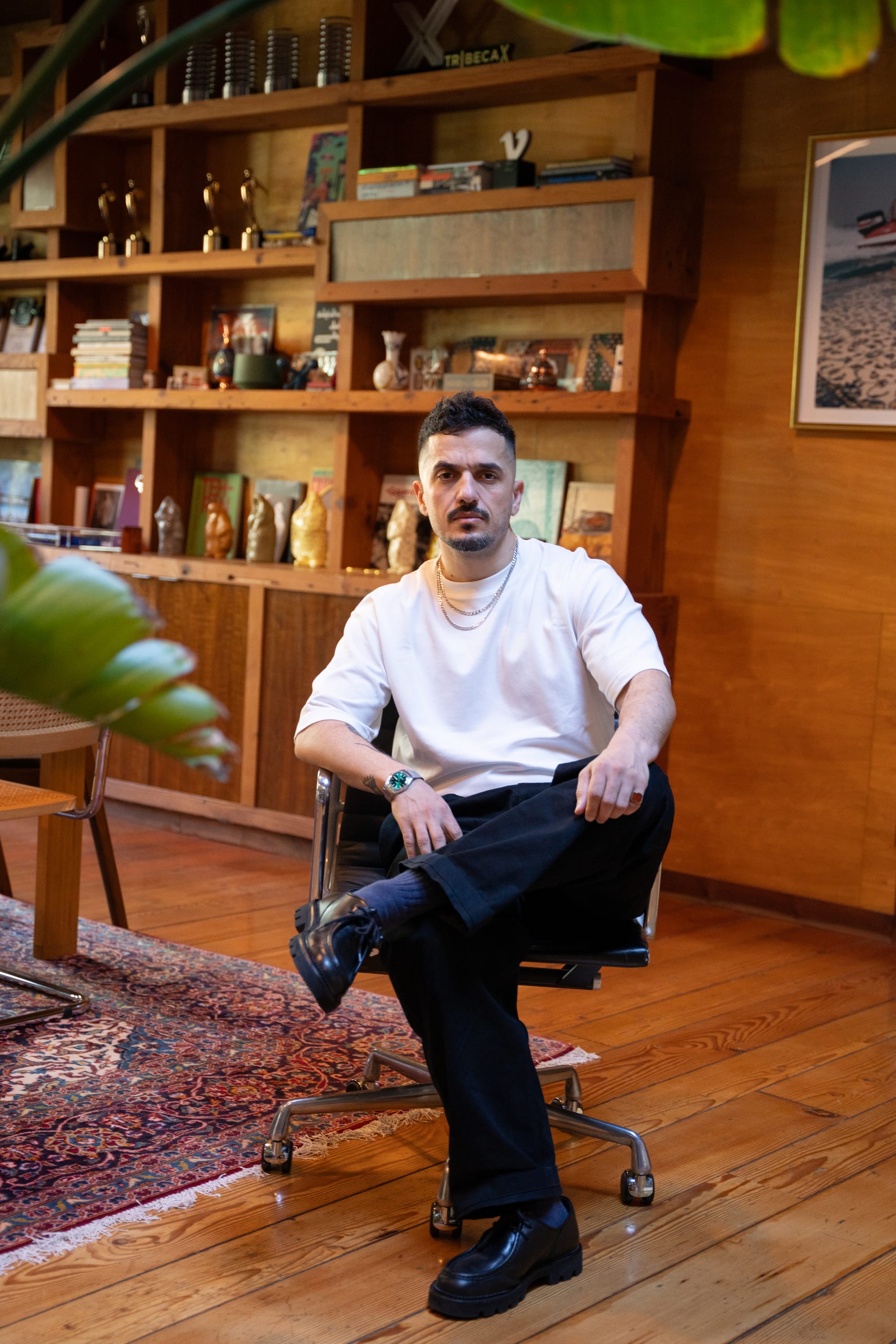 Man in a white t-shirt sitting in an office chair.