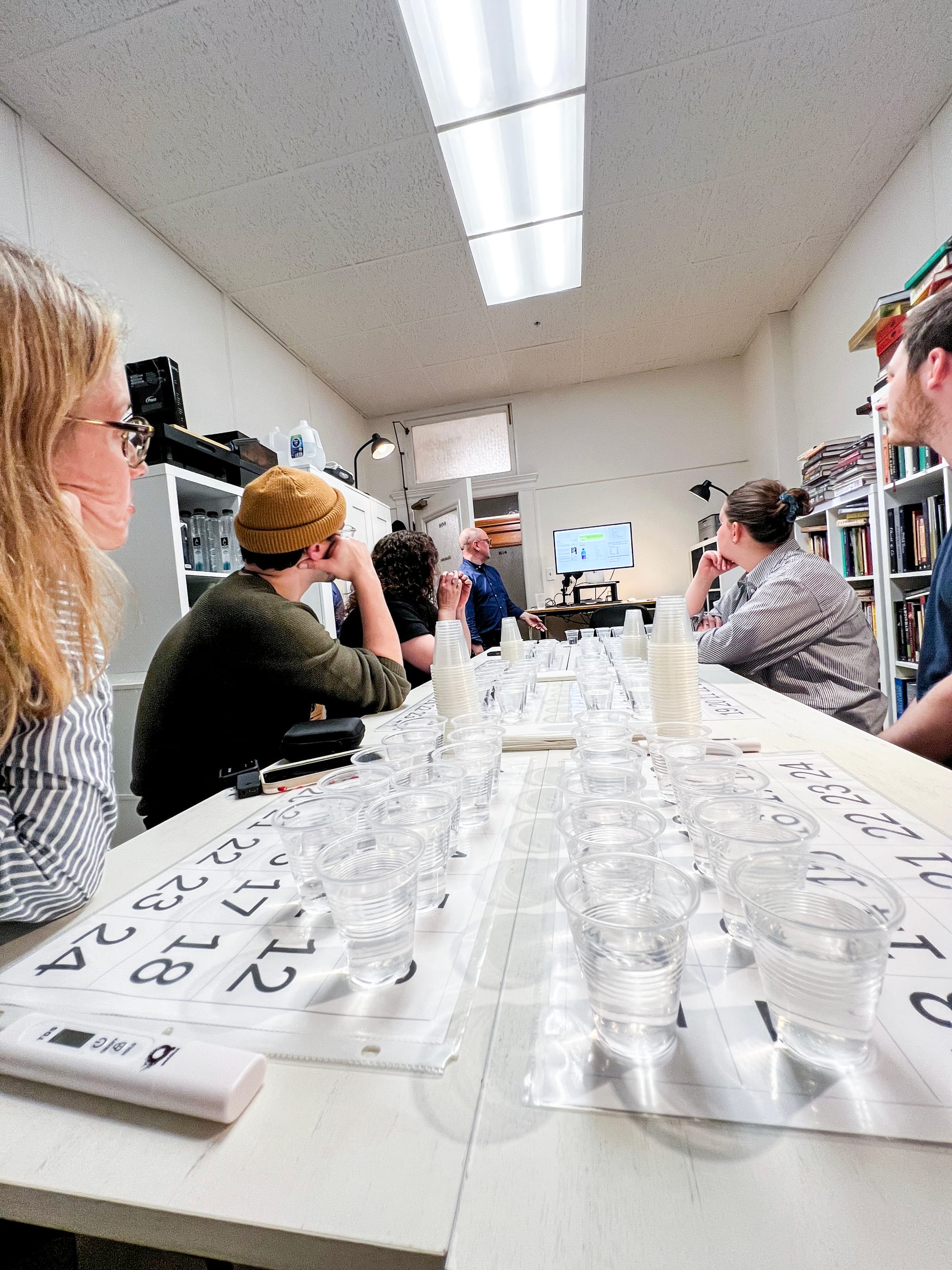 people sitting at a table filled with plastic cups full of water