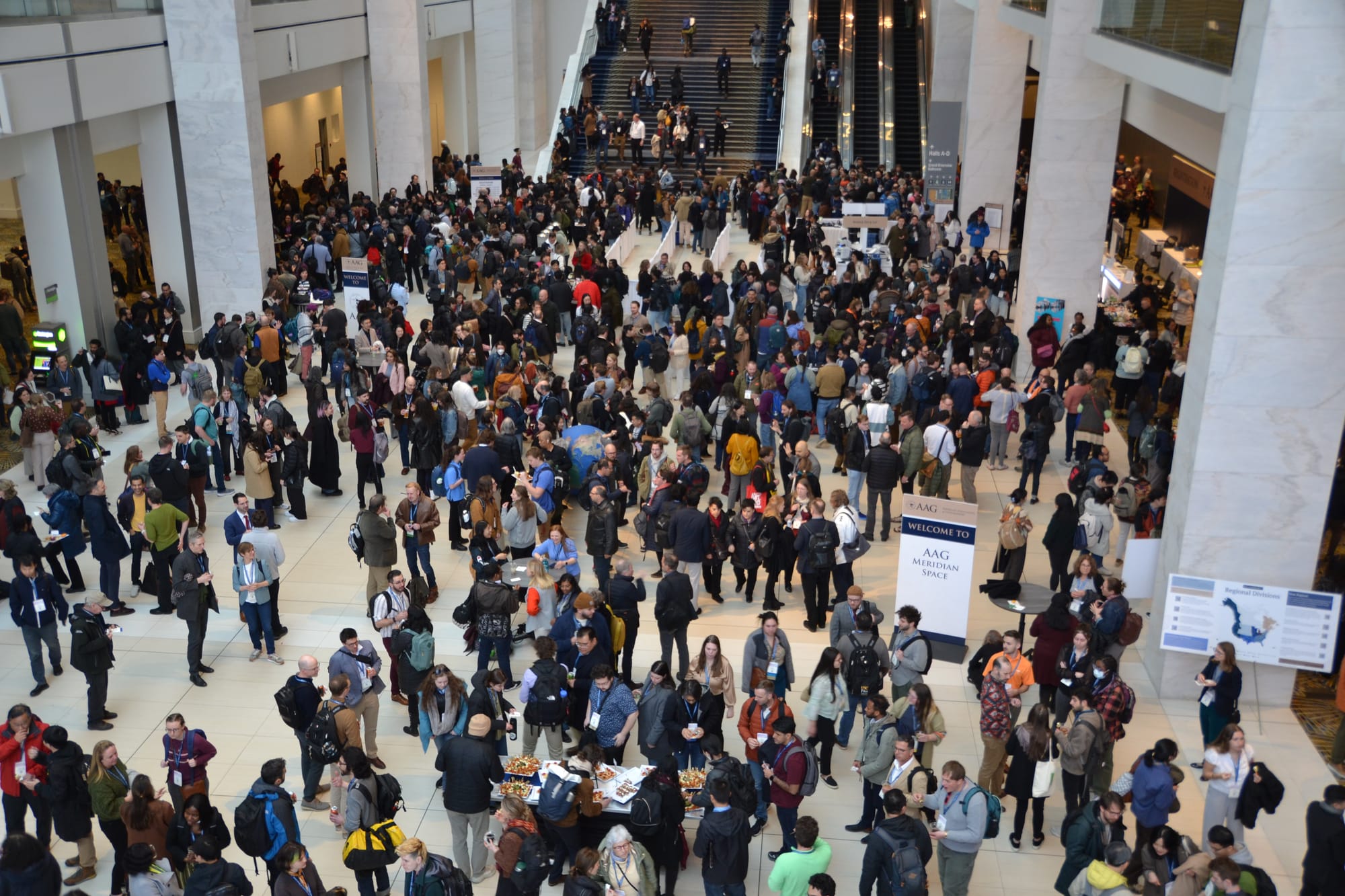 A crowd of people seen from above in a hotel lobby. 