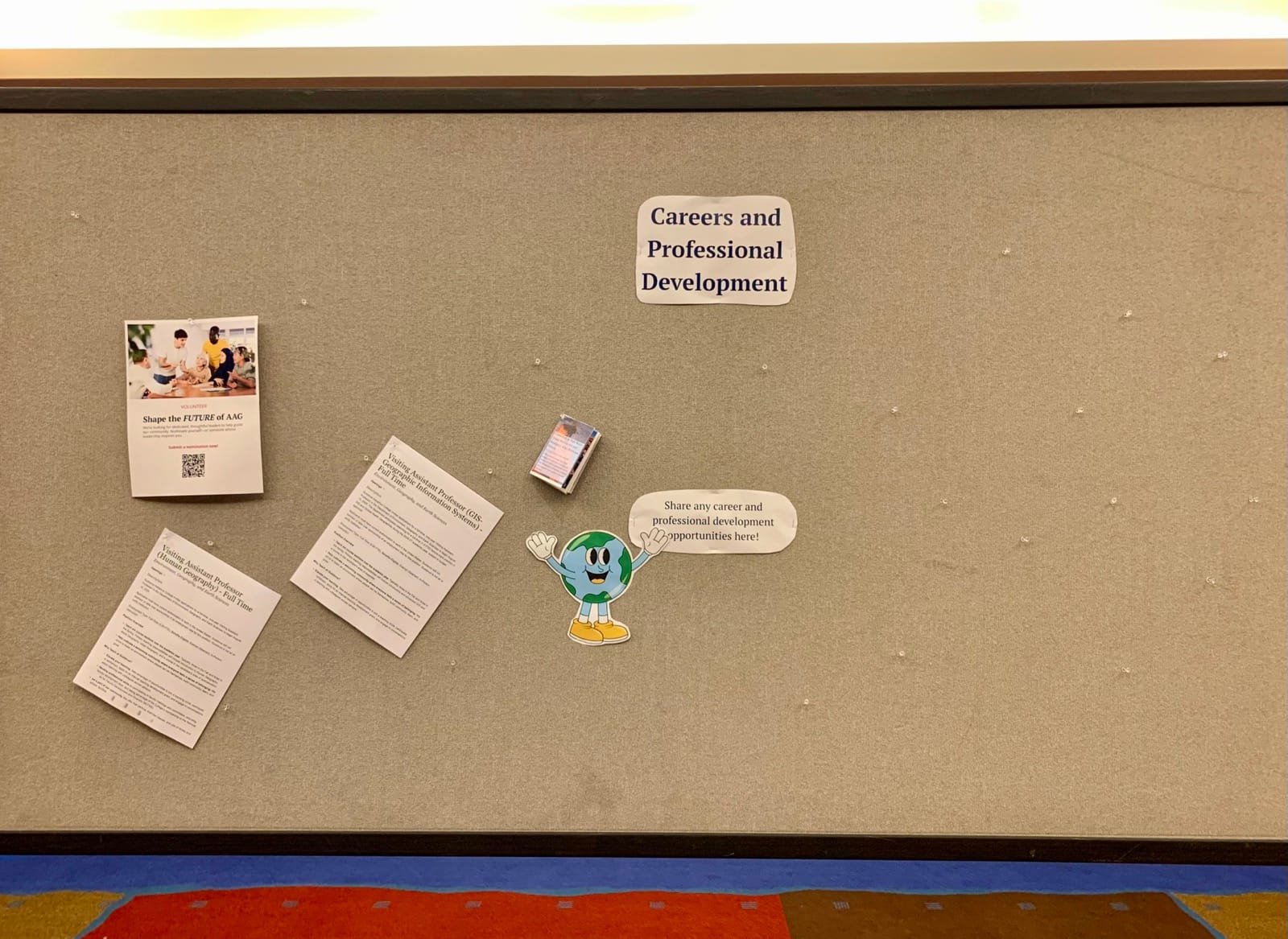A photo of a mostly empty jobs board. Near the top, a pushpin holds a sign reading āCareer and Professional Developmentā above a cartoon of a smiling globe with its arms open.