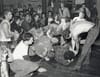 a black and white photo shows a chaotic punk show with people falling over