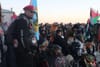 A man in sunglasses and a red beret standing in front of a crowd of people waving Indigenous and Palestinian flags.