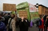 a protest with people holding cardboard signs that read 'your party is their misery' and 'where will you live after the bubble bursts'