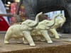 Three small identical white elephants sit on a shelf