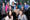 4 shots of 11 people posing on a balcony with trees in the background.